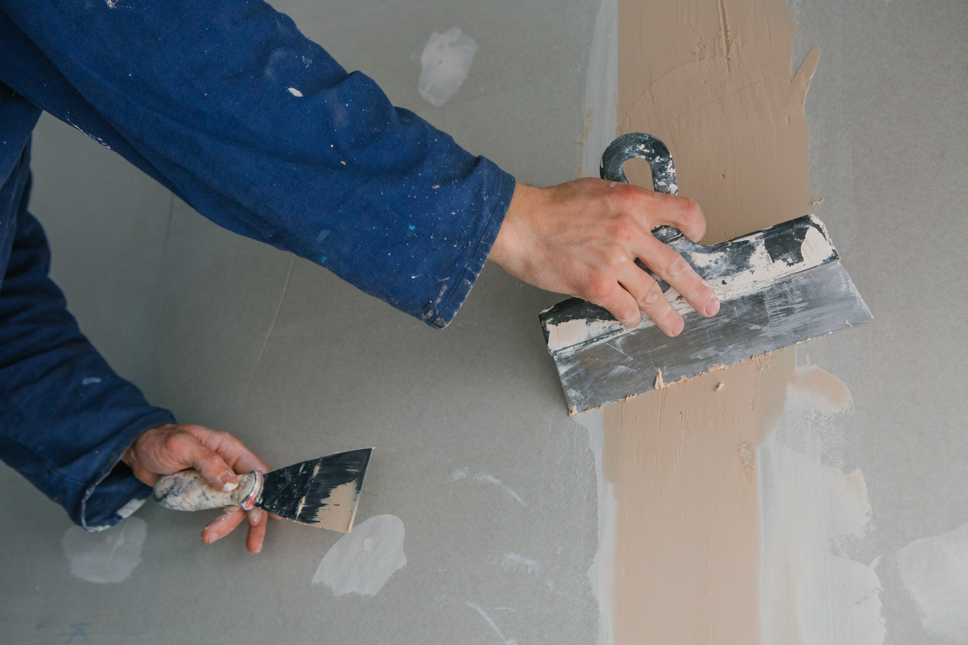 plasterer-man-works-plastering-two-trowels-plasterboard-blue-uniform (1)